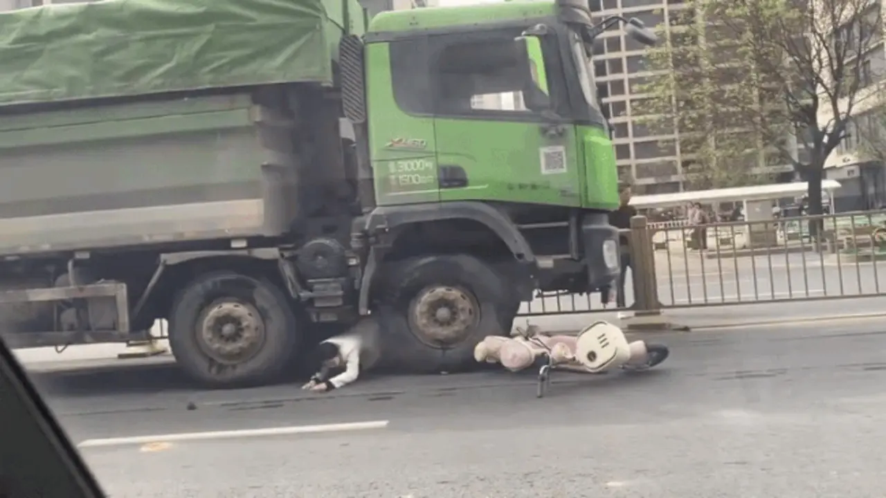 Người phụ nữ đi xe máy chui ra từ gầm xe ben